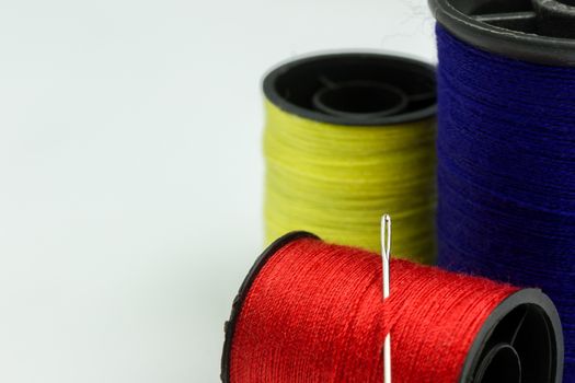 Close up Thread roller Blue, Red, Yellow and Sewing Needles in white background.Use to repair the tear of clothing.