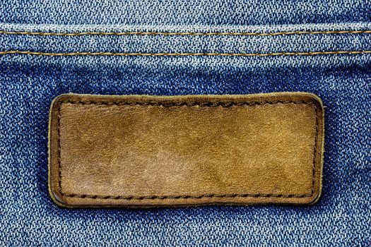 Blank brown leather label on vintage blue jeans. Suitable for backgrounds, articles about fashion clothing.