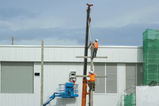 Workers in a baskets are installing building a factory and red crane