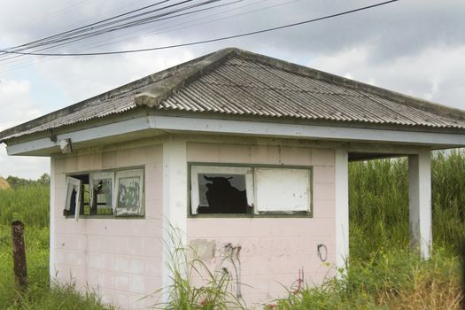 An abandoned house in a green forest with broken glass.