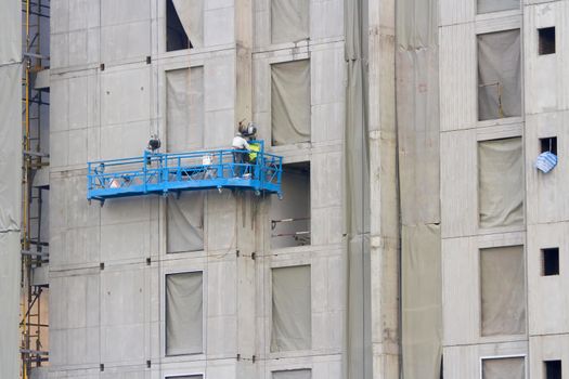 Construction baskets blue next to the building with workers