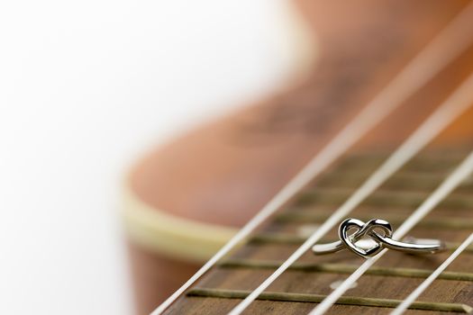 Heart shaped ring laying on ukulele string. The concept of a musician lover. Copy space can be used to write articles about Valentine's Day.