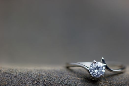 Closeup fake diamond ring placed on brown leather jecket. The concept of love or marriage. Copy space can be used to write articles about Valentine's Day.