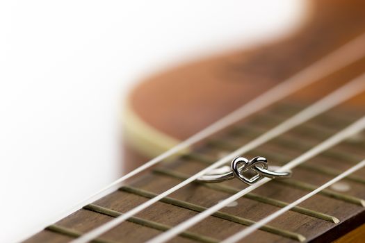 Heart shaped ring laying on ukulele string. The concept of a musician lover. Copy space can be used to write articles about Valentine's Day.