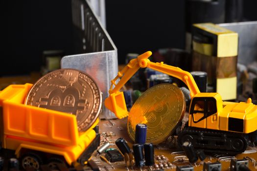 Backhoe dig bitcoin on mainboard put in the truck. Concept of bitcoin mining business.