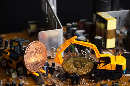 Backhoe and forklift dig bitcoin on mainboard. Concept of bitcoin mining business.
