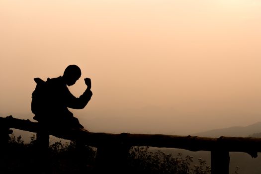 Silhouette men are happy or successful at the viewpoint of sunset going down in the mountains on evening.