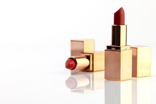 Red lipstick in golden box on white background.