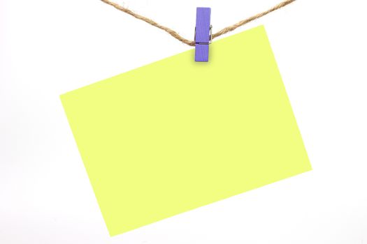 The blue wooden clip clamped the yellow note with the hemp rope.