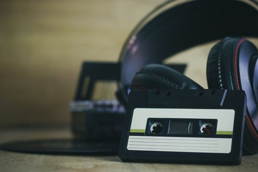 Cassette and headphone with gramophone record platter on wood background. The concept of love in music.