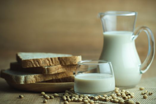 Soybean milk in a glass jug and whole wheat bread in wood disk on table. The concept of healthy breakfast.