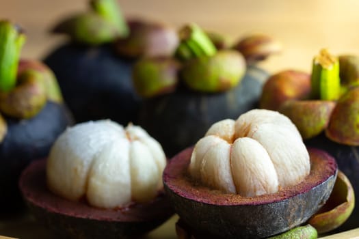 Mangosteen was peeled in a plate on a wooden table.