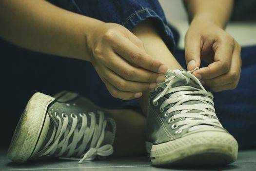 Women sit on the floor and lace up sneakers. The concept of travel or adventure.