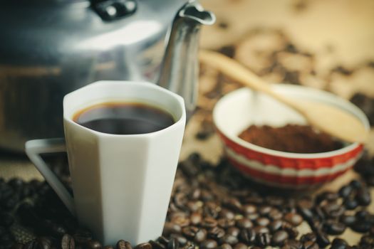 Coffee cup and hot pot. Roasted coffee beans on brown wood background in morning.