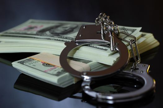 Handcuffs and money in the darkness. Concept of Business fraud and Corruption.