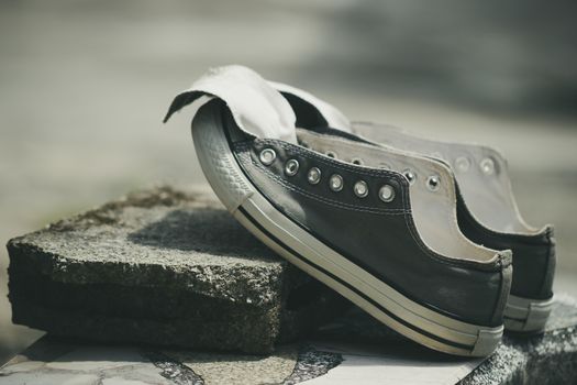 Old sneakers put on a piece of cement in the hot sun.