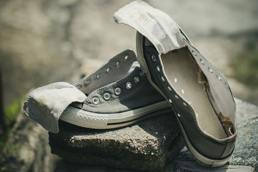 Old sneakers put on a piece of cement in the hot sun.