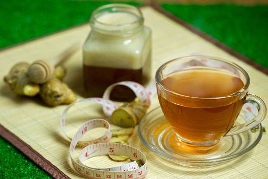 Ginger juice in a clear cup and honey jar placed beside with measuring tape.
Concept of healthy.