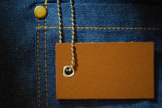 Leather label of product price and stainless steel ball chain on denim clothing. The concept of Fashion jeans.