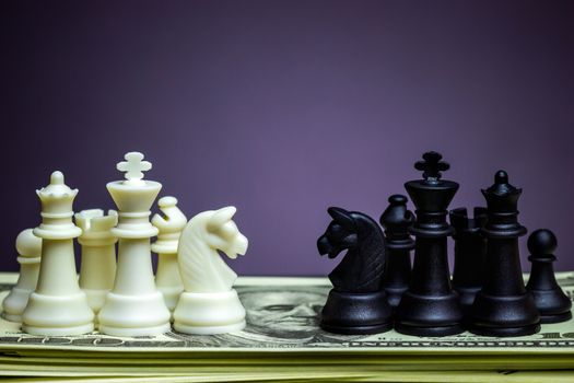 Both white and black chess face each other on a dollar banknote. Concept of business strategy or business war.