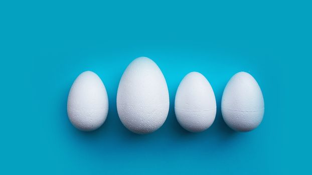 White foam eggs on blue background. Flat lay, top view. Easter concept.