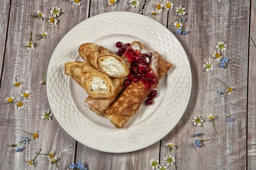 Plate with pancakes with meat and cup of tea on an old wooden background