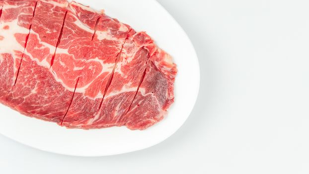 Top view of some raw beef on a plate over white background