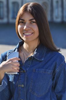 Portrait of a young girl on the street who listens to music with headphones