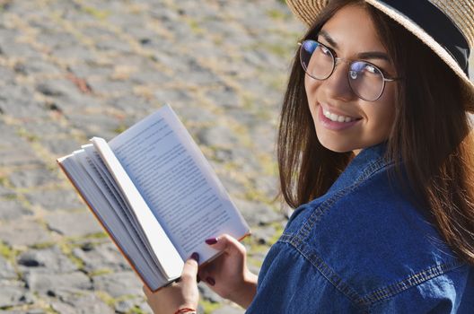 Portrait of a girl in glasses Asian appearance who holds an open book