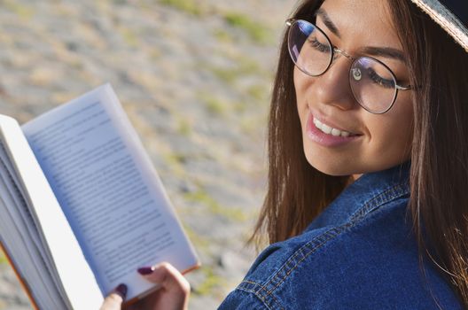 Portrait of a girl in glasses Asian appearance who smiles and holds an open book
