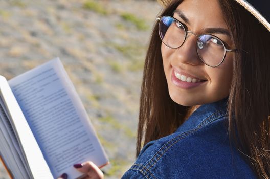 Portrait of a girl in glasses Asian appearance who holds an open book