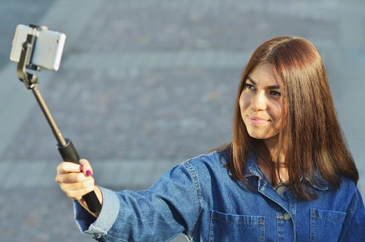 Brunette girl Asian looks in a denim suit takes a selfie and smiles