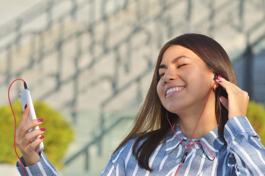 Beautiful girl smiling and listening to music in headphones on a Sunny day