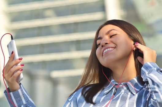 Young beautiful brunette listening to music in headphones on the street