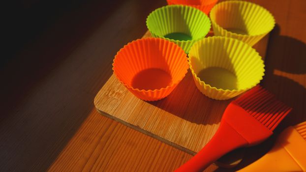 Silicone brush and cupcake liners on wooden table. Kitchen and cooking concept on wooden background