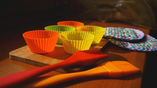 Silicone brush and cupcake liners on wooden table. Kitchen and cooking concept on wooden background