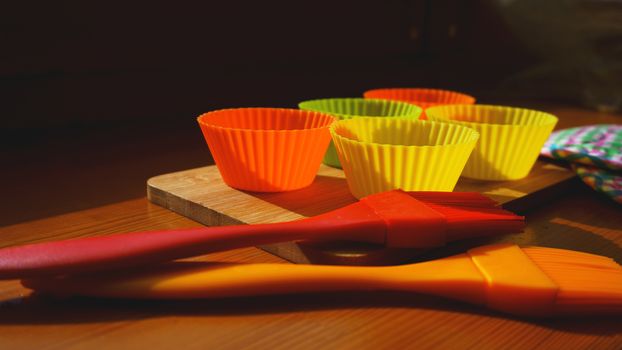 Silicone brush and cupcake liners on wooden table. Kitchen and cooking concept on wooden background