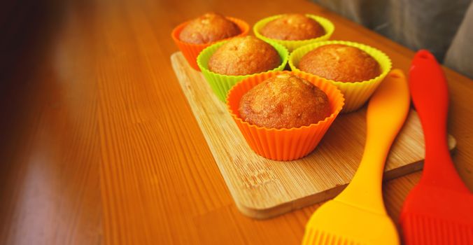 Simple mini muffins in colorful silicone bakeware. Silicone cup baking cupcakes and silicone brushes. Kitchen and cooking concept on wooden background