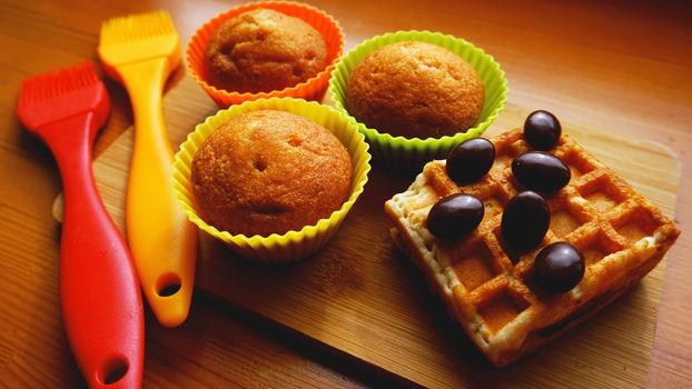 Simple mini muffins in colorful silicone bakeware and waffles. Kitchen and cooking concept on wooden background