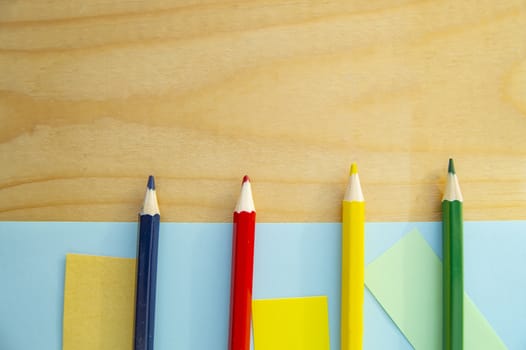 Flat lay, colored pencils, blue and wooden background, back to school, copy space.