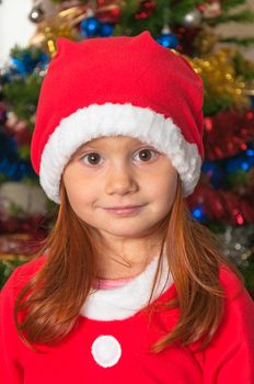 little redhair girl dressed as Santa Claus, background Christmas decorations