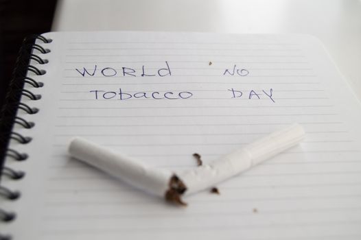 World no tobacco day, no Smoking day. Broken cigarette on business notebook, minimalism.