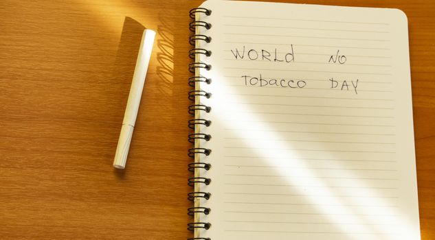 Flat lay, cigarettes and the inscription world no tobacco day written in a notebook, a healthy lifestyle without cigarettes.