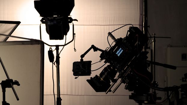 Video camera in film or movie production on tripod and professional gear which shooting in location or studio with crew team and beautiful prop or set and ready to online live broadcast or tv on air later 