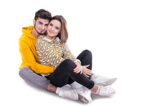 Young couple in yellow hugging and sittin in white studio