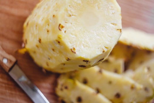 Pineapple cleaning, chunks, knife lie on the board.