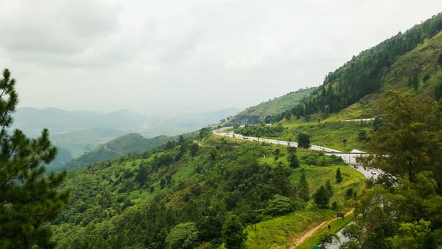 View of the Paraíba do Sul River Valley, São Paulo, Brazil, with hills covered with forest and freeway in the background on foggy day.