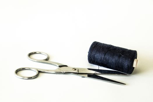 Open scissors cutting a blue thread