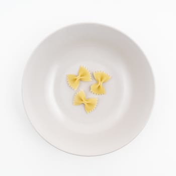 Three pieces of dried butterfly format pasta on the plate