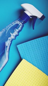 Housework, housekeeping and household concept - cleaning rag, detergent spray on blue background